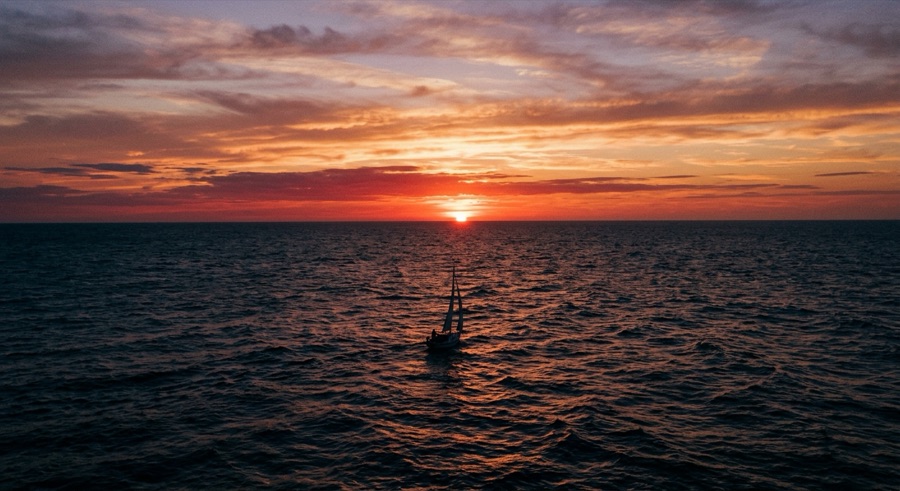 Story frame 3: sailboat on the open sea at sunset
